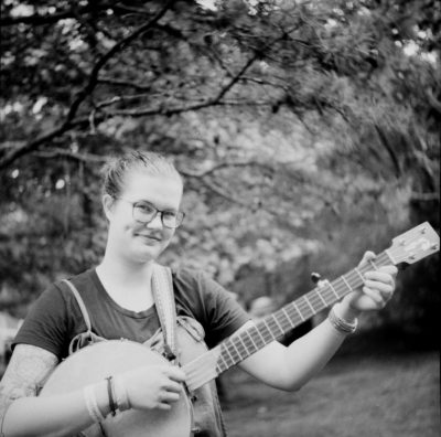 White person plays the banjo and smiles, black and white 