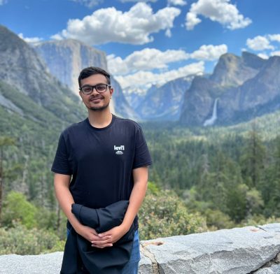 Indian man stands in front of beautiful mountains 
